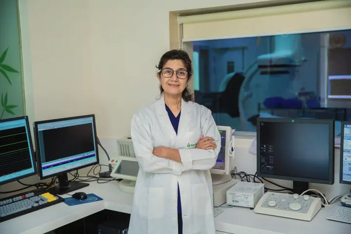A doctor with her arms crossed stands beside monitoring screens in a medical laboratory in Delhi.