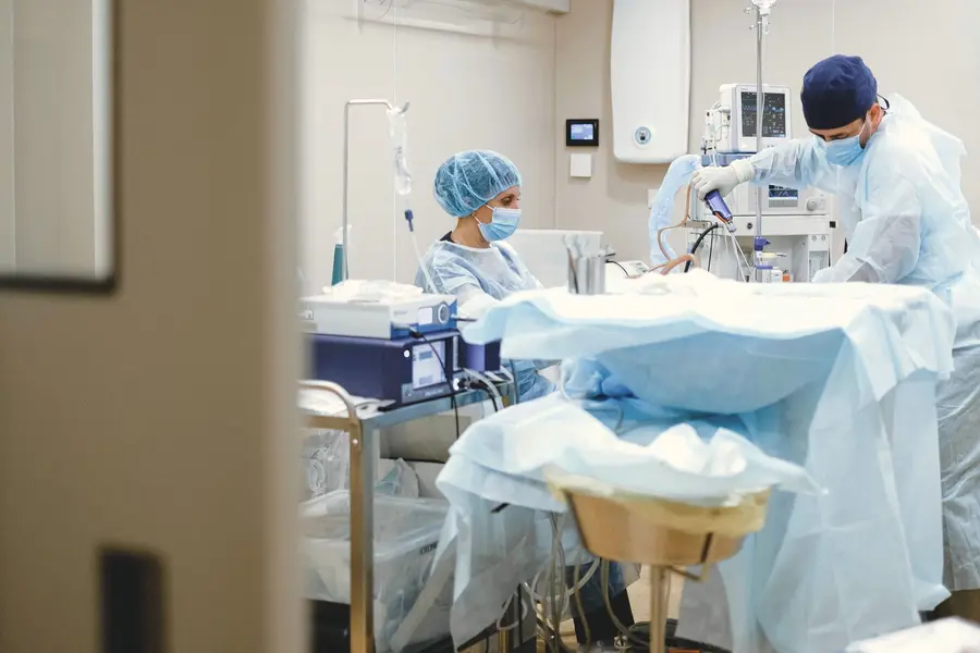 A surgeon and a nurse at work in a bright operating room.