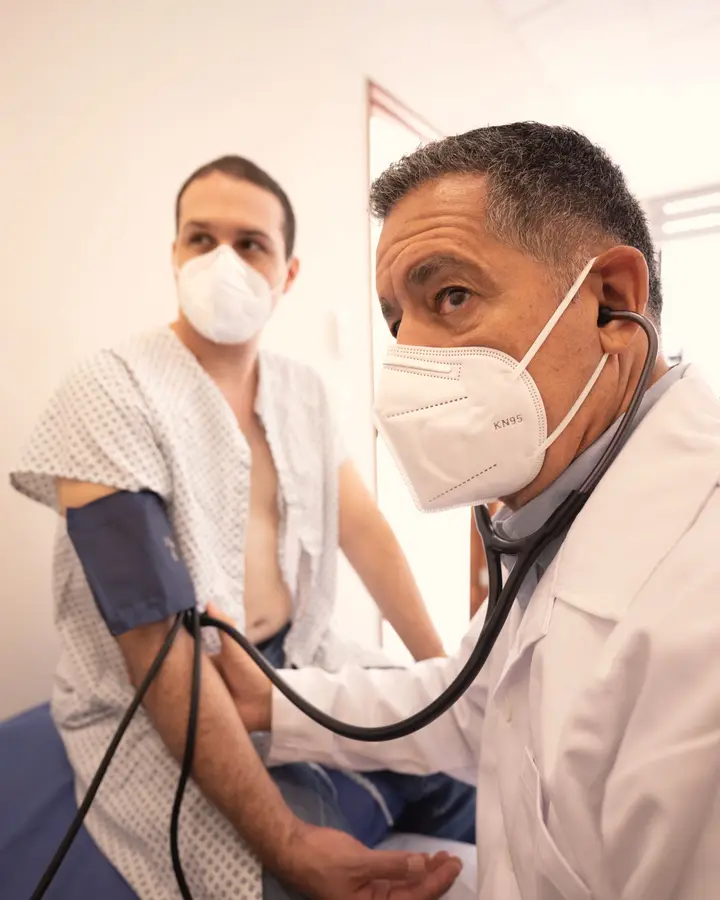 A doctor listens with a stethoscope while measuring a patient's blood pressure.