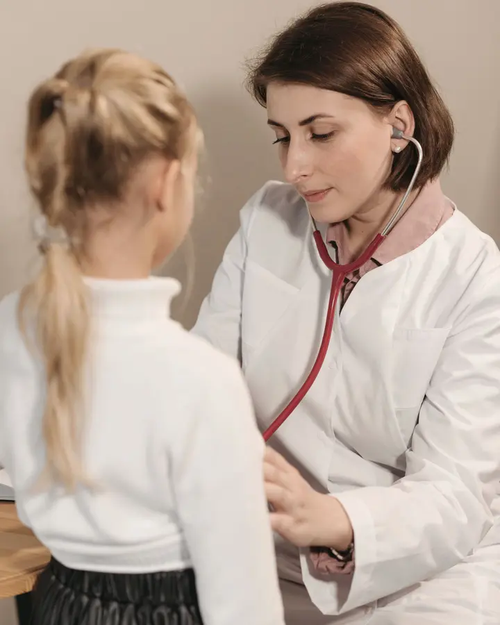 A doctor listens to a young girl's chest with a stethoscope.